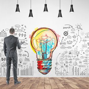 Rear view of a young businessman in a gray suit holding a folder. He is looking forward. A good business idea and a start up mind map on a concrete wall